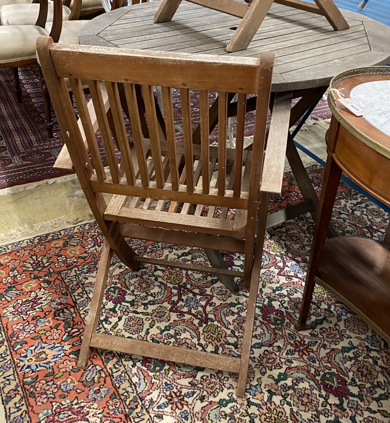 A circular weathered teak folding garden table, diameter 100cm, height 73cm and two elbow chairs